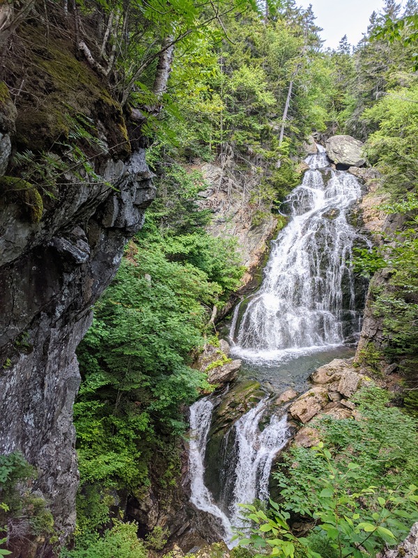 A large waterfall flowing over mossy rock in the forest