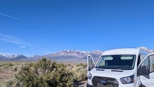 a photo of a white cargo van with sagebrush and mountains